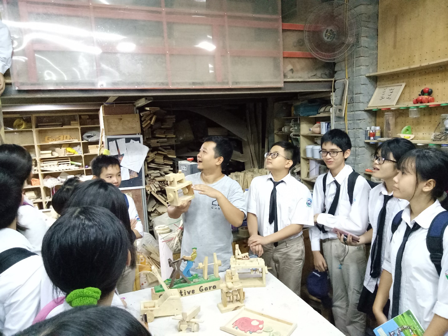 Học sinh chú tâm lắng nghe chú Phạm Quý Phúc- giám đốc điều hành CREATIVE GARA giới thiệu các dụng cụ, đồ nghề, sản phẩm mộc của xưởng
