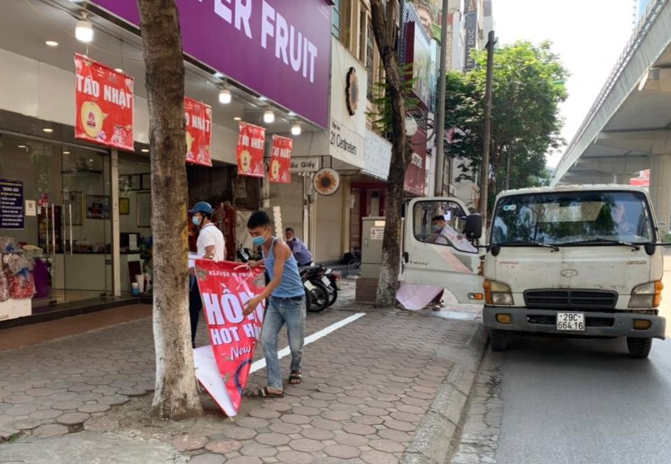 Lực lượng chức năng phường Dịch Vọng xử lý biển hiệu, biển quảng cáo sai quy định trên các tuyến đường.