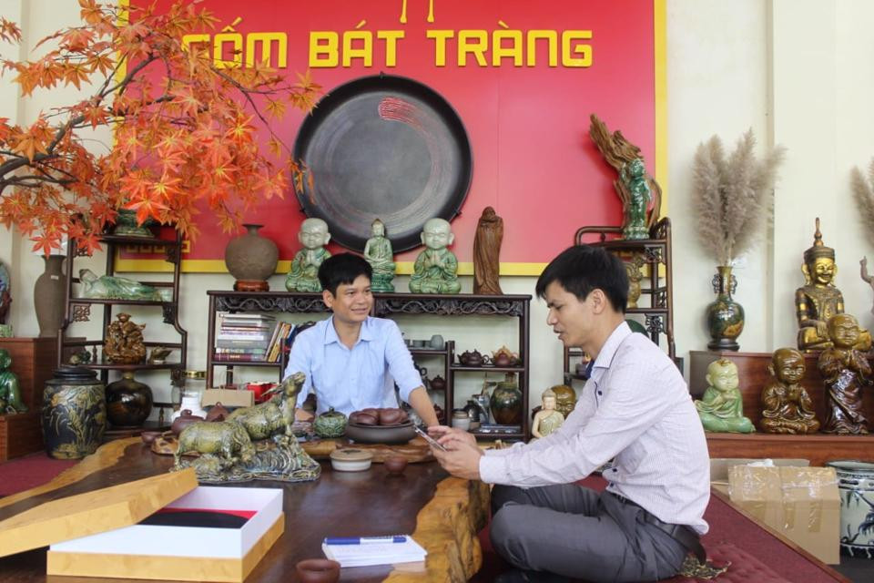 Giám đốc Công ty Cổ phần Sứ Việt Vũ Văn Đức (bìa trái) trao đổi với lãnh đạo xã Bát Tràng về ý tưởng thiết kế các sản phẩm quà tặng, lưu niệm nhân dịp SEA Games 31