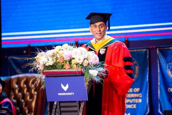 A person in a graduation gown and cap standing at a podium with flowers AI-generated content may be incorrect.